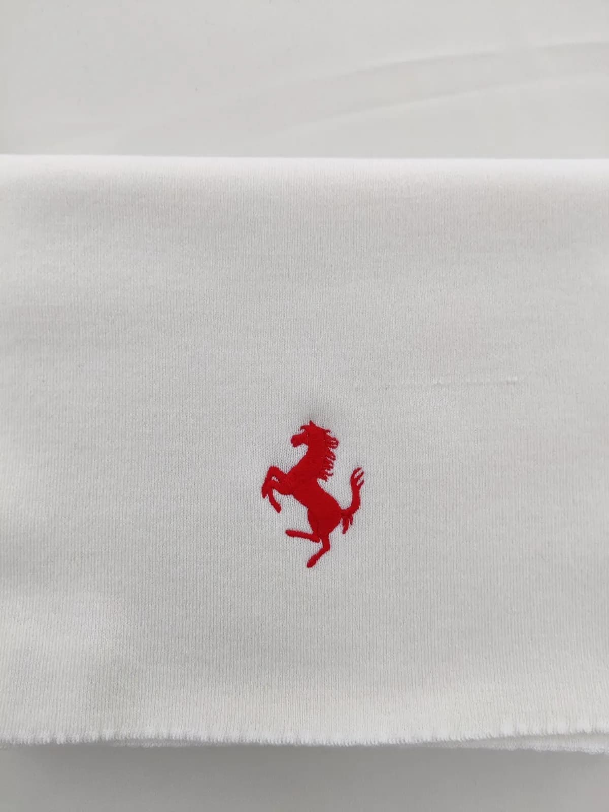 White scarf embroidered with a small red Ferrari prancing horse logo