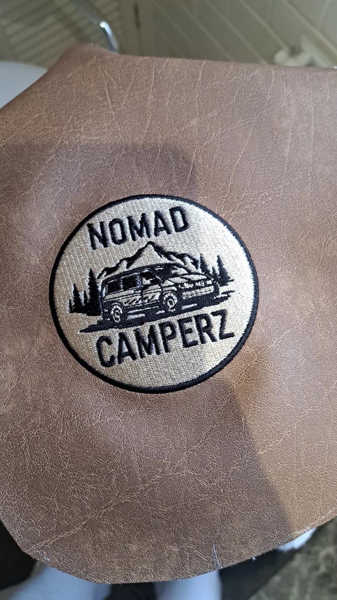 Nomad Camperz embroidered patch on a leather headrest panel