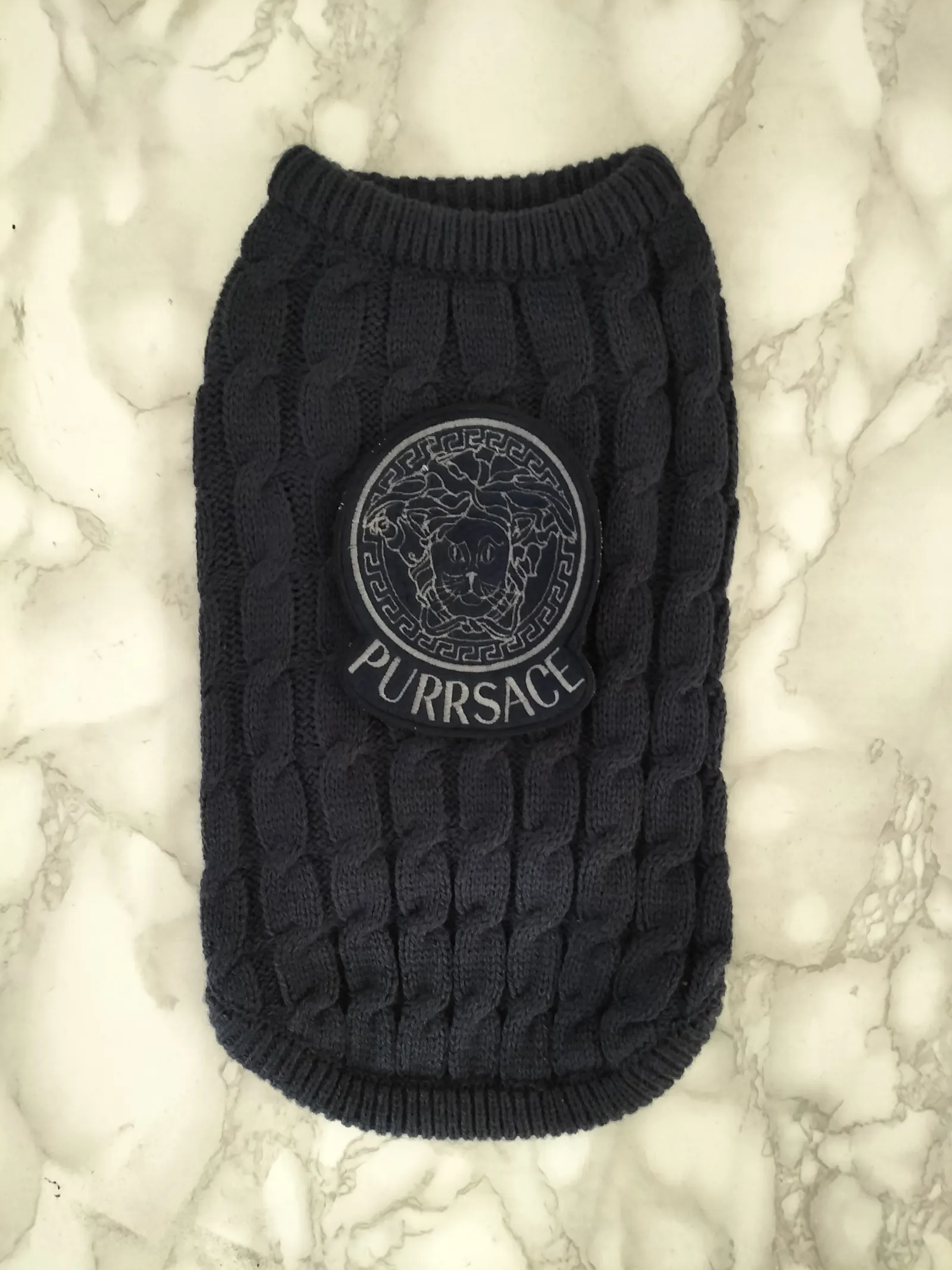 Grey cable-knit pet jumper embroidered with a playful 'Purrsace' logo, made as a production prop